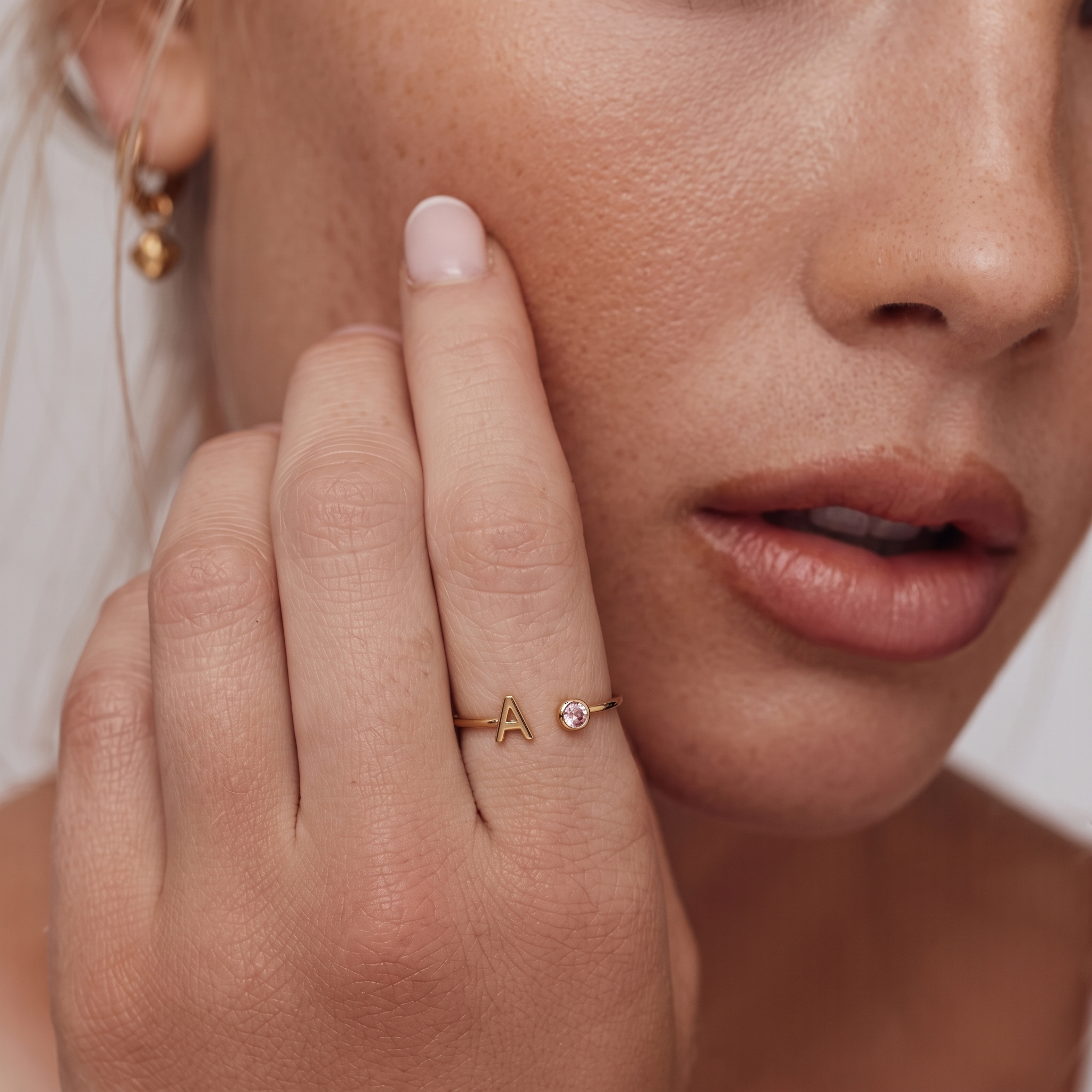 Prsten Celine s písmenem A a růžovým kamenem na ruce modelky