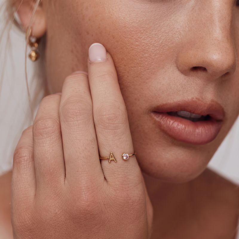 Prsten Celine s písmenem A a růžovým kamenem na ruce modelky